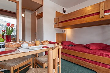 A room with a bunk bed and a table with a loaf of bread on it