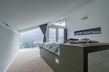 A bedroom with a bed and a picture of mountains on the wall