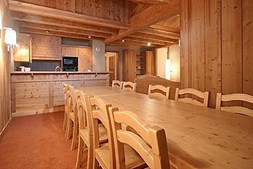 A dining room with a long wooden table and chairs