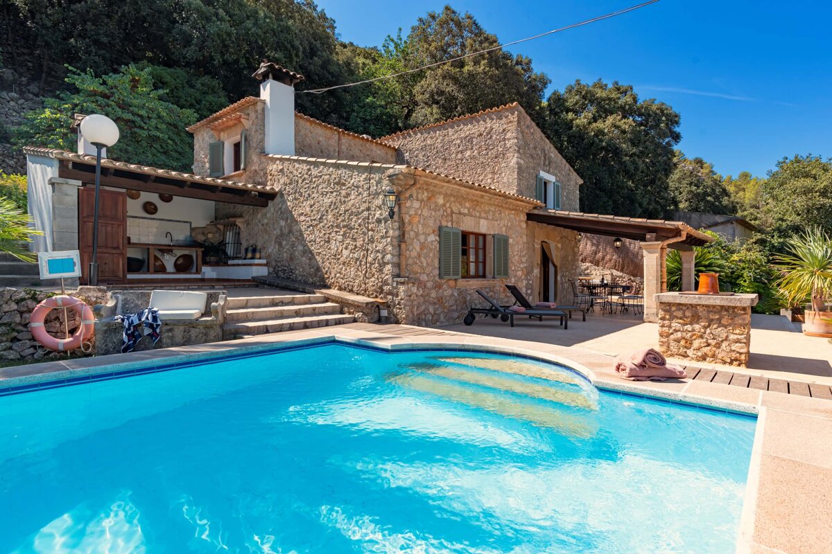 A large stone house with a swimming pool in front of it