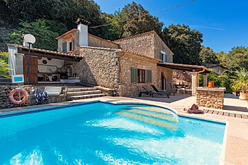 A large stone house with a swimming pool in front of it