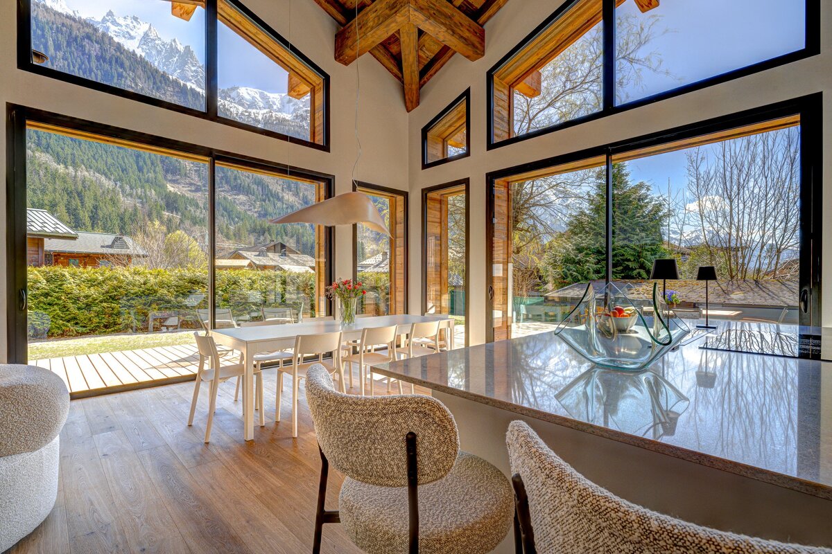 A dining room with a table and chairs and a view of the mountains