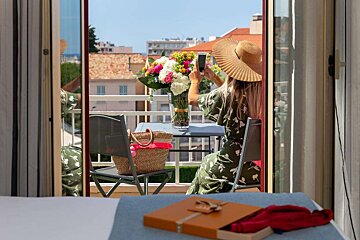 A woman taking a picture of flowers on a balcony