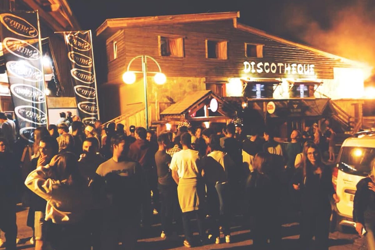 A lively crowd gathers outside a wooden 