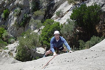 a picture of a man climbing up a smooth rock on a rope
