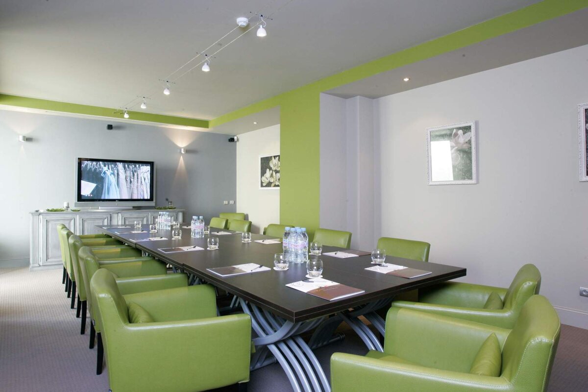 A conference room with a long table and green chairs
