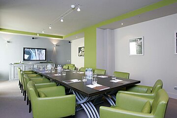 A conference room with a long table and green chairs