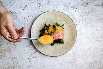 A person is holding a spoon over a plate of food