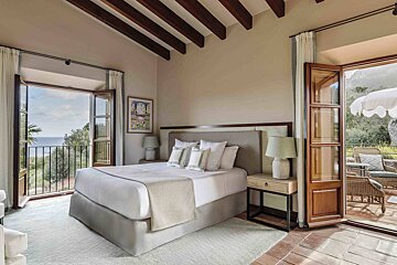 A bedroom with a large bed and a balcony