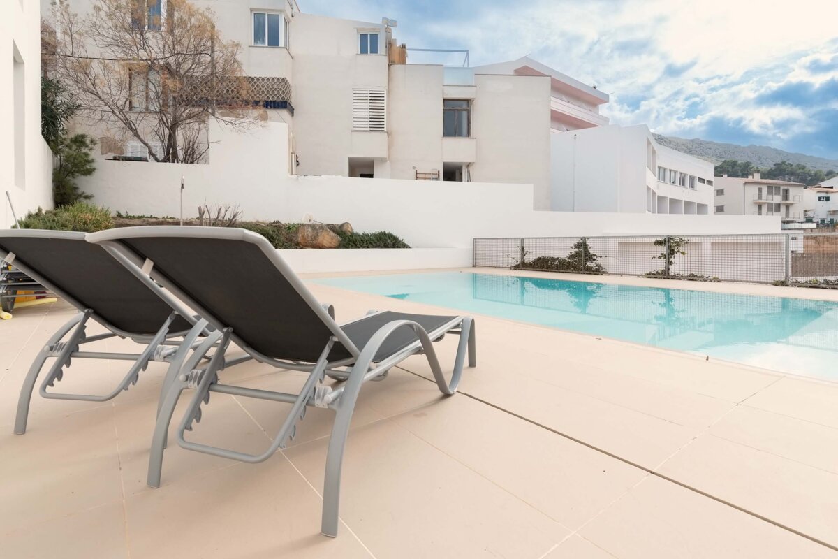 A swimming pool with two lounge chairs in front of it