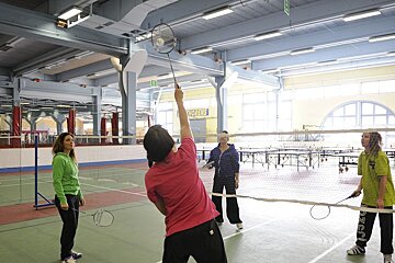 A group of women are playing badminton in a gym