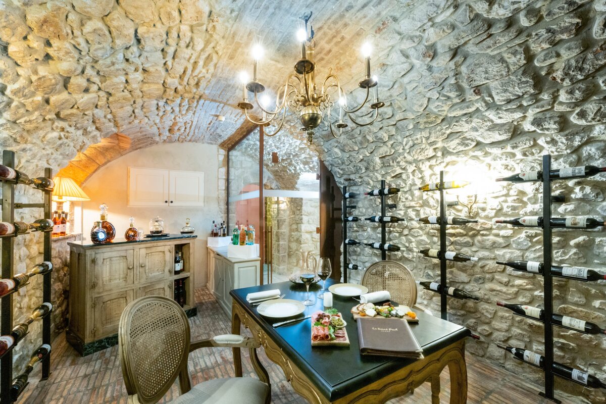A wine cellar with a table and chairs and bottles of wine