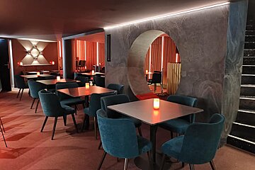 A restaurant with tables and chairs with candles on them