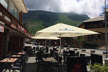 Tables and chairs under a large umbrella that says
