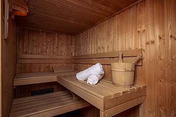 A wooden sauna with a bucket and a towel on the bench