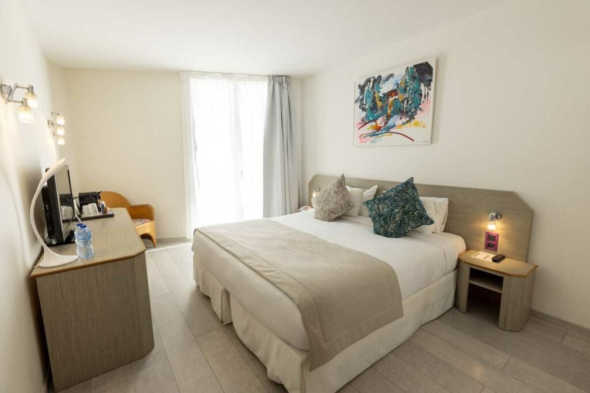 A hotel room with a painting on the wall above the bed