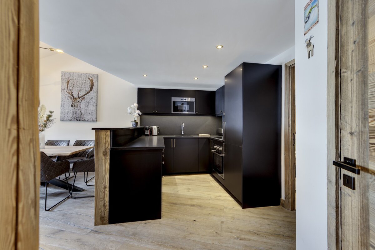 A kitchen with black cabinets and a painting of a deer on the wall