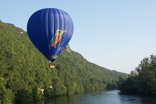 a blue hot air balloon above the dordogne river