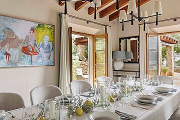 A dining room with a long table and a painting on the wall