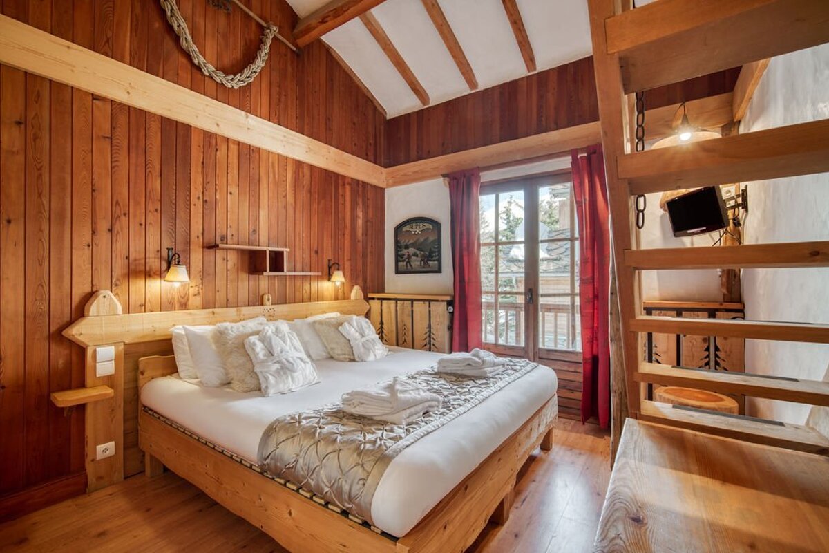 A wooden bedroom with a king size bed and stairs