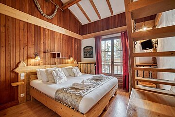 A wooden bedroom with a king size bed and stairs