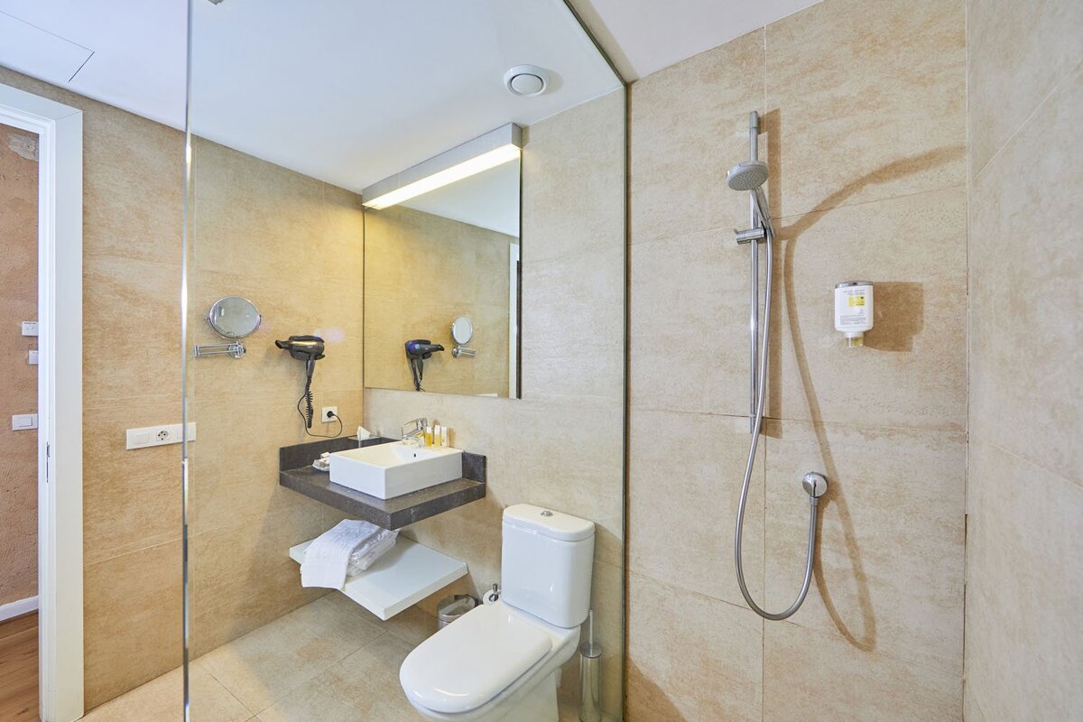 A bathroom with a toilet a sink and a shower