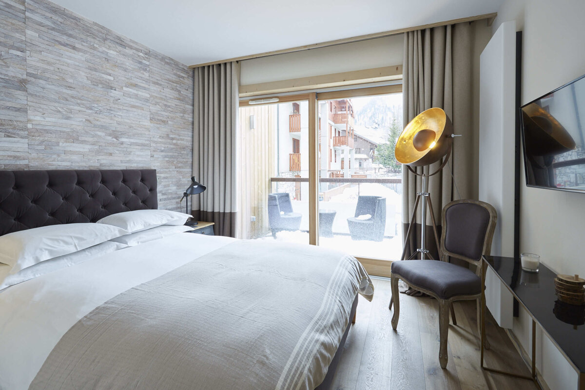 A bedroom with a large bed a chair and a television