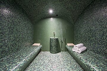 A green tiled room with two benches and a sink