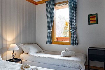 A bedroom with two beds and a window with plaid curtains