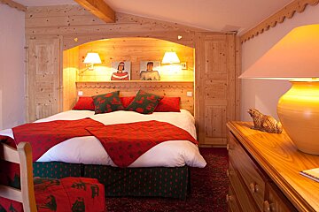 A bedroom with a bed and two pictures on the wall