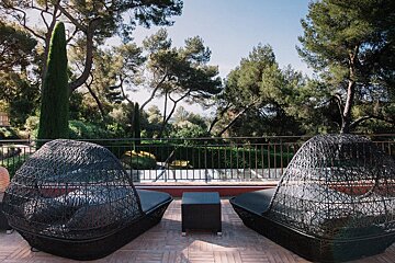 Two wicker chairs on a balcony with trees in the background