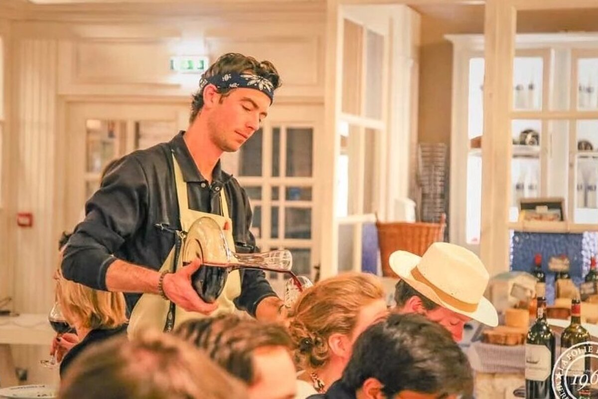 A man in a bandana is pouring wine into a glass