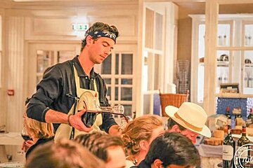 A man in a bandana is pouring wine into a glass