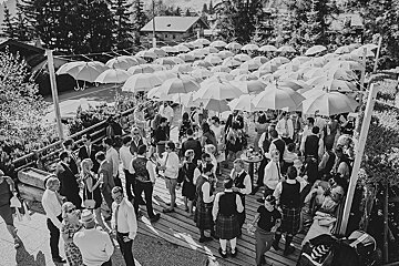 A black and white photo of a group of people standing under umbrellas