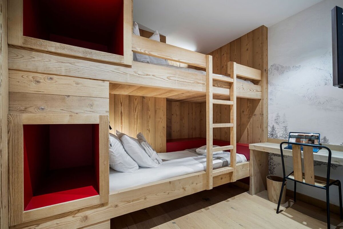 A bunk bed in a room with a desk and chair