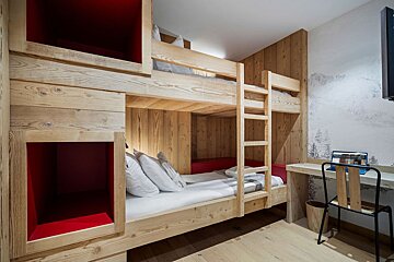A bunk bed in a room with a desk and chair