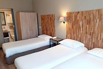 A hotel room with two beds and a wooden headboard
