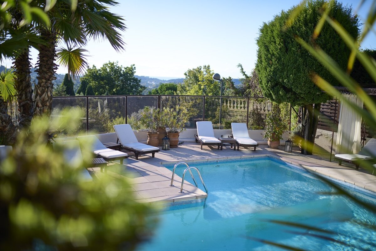 A swimming pool surrounded by chairs and palm trees