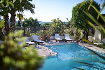 A swimming pool surrounded by chairs and palm trees