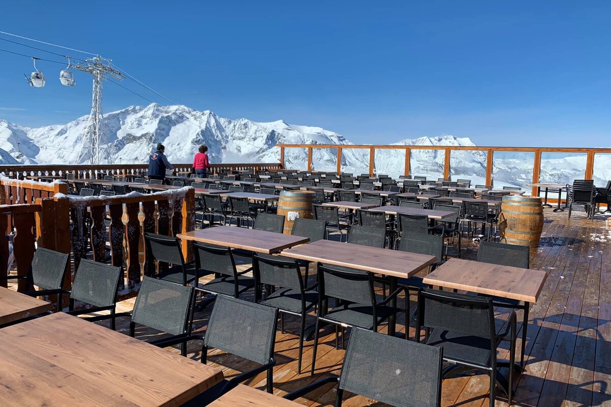 Tables and chairs on a deck with mountains in the background
