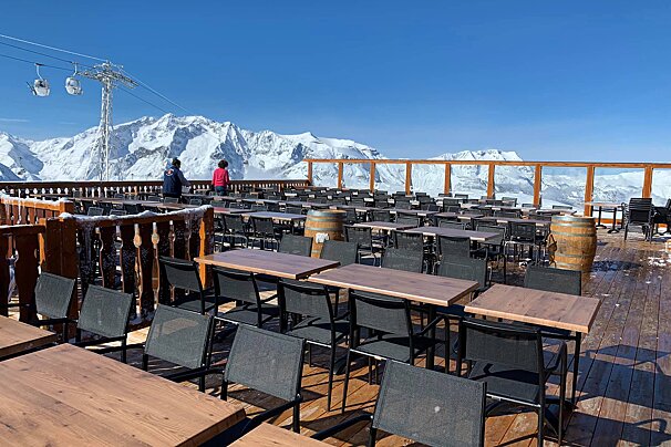 Tables and chairs on a deck with mountains in the background