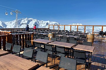 Tables and chairs on a deck with mountains in the background