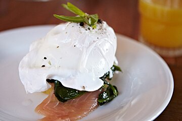 A white plate topped with a poached egg and spinach