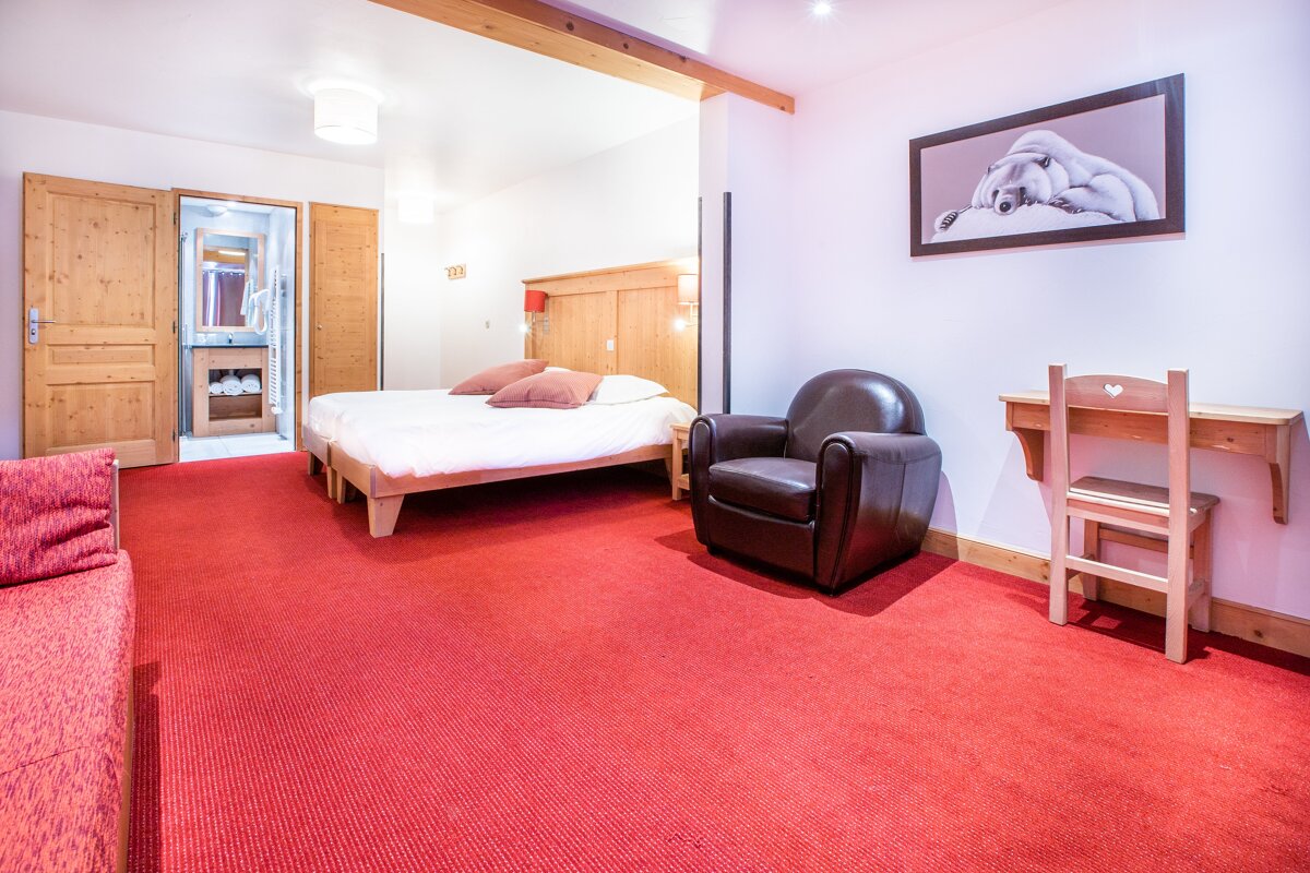 A bedroom with a bed a chair and a desk