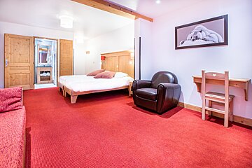 A bedroom with a bed a chair and a desk