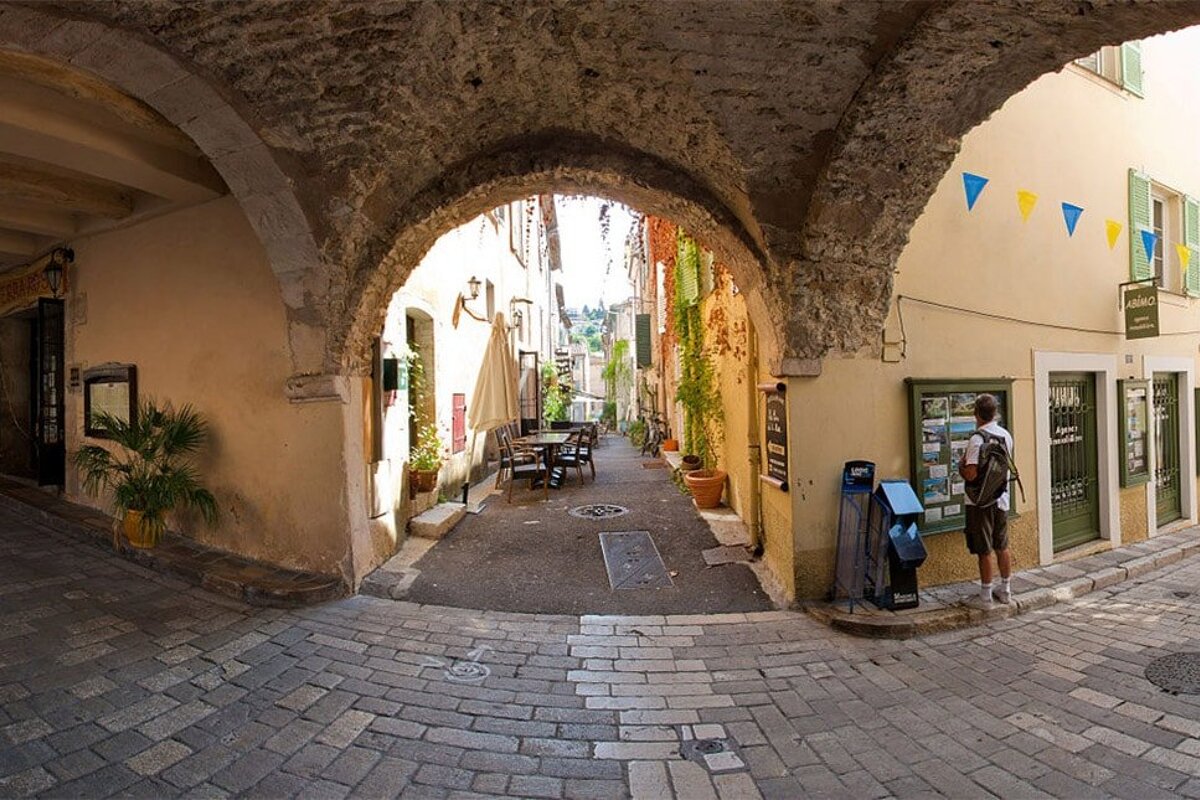 A man stands in a narrow alleyway in front of a sign that says ' tourisme ' on it