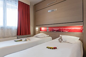A bedroom with two twin beds and a teddy bear on the bed
