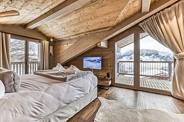 A bedroom with a large bed and a flat screen tv