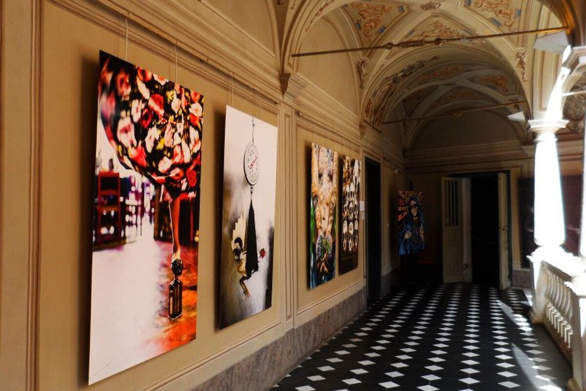 A hallway with paintings on the wall and a checkered floor