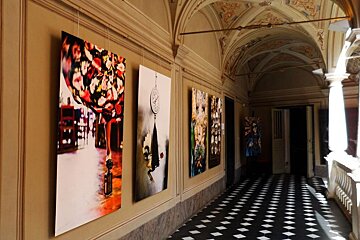 A hallway with paintings on the wall and a checkered floor